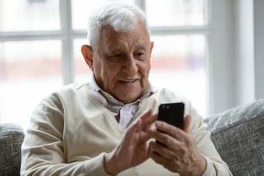 Close up smiling older man using phone, looking at screen