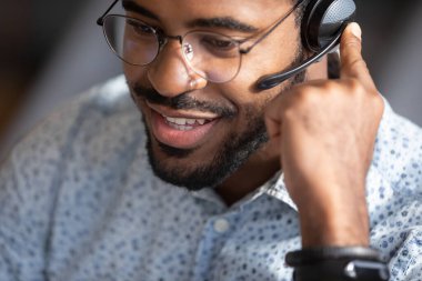 African call center operator wears headset contacting with customers closeup clipart