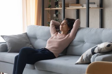 Relaxed satisfied young woman resting on cozy couch at home
