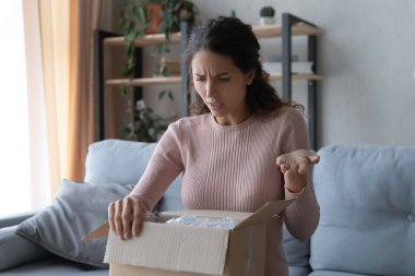Angry confused woman unpacking parcel, wrong or broken order