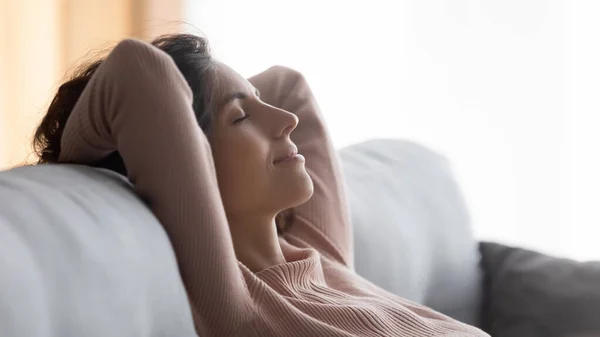 Close up sognante donna soddisfatta che riposa su un accogliente divano — Foto Stock