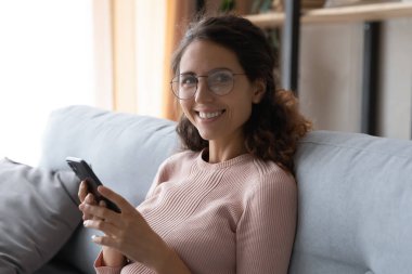Head shot portrait smiling woman wearing glasses holding smartphone