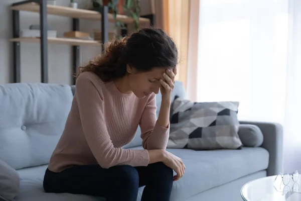 Unhappy stressed woman touching forehead, sitting on couch alone — Stock Photo, Image