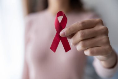 Close up female hand holding red awareness ribbon