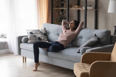 Relaxed peaceful woman relaxing on cozy couch in living room