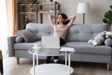 Smiling peaceful young woman relaxing, leaning back on couch