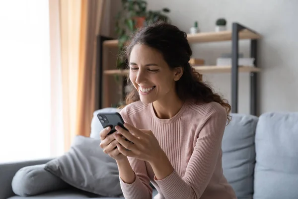 Overjoyed woman with toothy smile looking at phone screen — Stockfoto