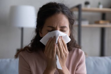 Close up sick woman blowing nose, holding paper tissue