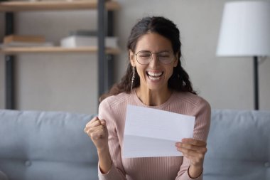 Close up overjoyed laughing woman wearing glasses reading letter