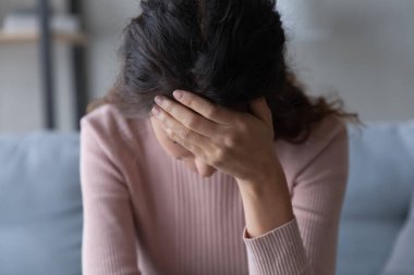 Close up unhappy depressed young woman touching forehead