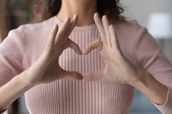 Close up young woman showing heart gesture with fingers — Stock Photo, Image