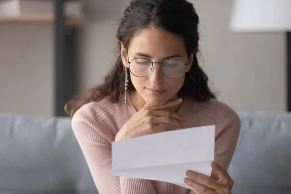 Close up focused serious woman wearing glasses reading letter