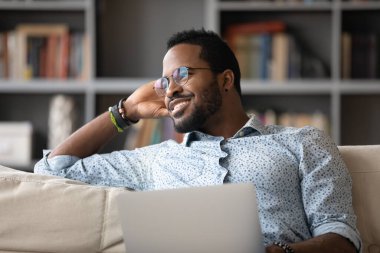 African guy distracted from using laptop daydreams looking at window
