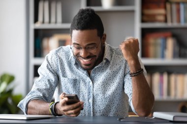 Excited African man looking at smartphone screen read unbelievable message