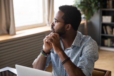 Guy sitting at table pondering over problem looking at distance