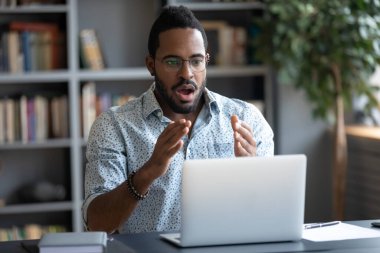 African guy feels shocked looking with amazement at laptop screen