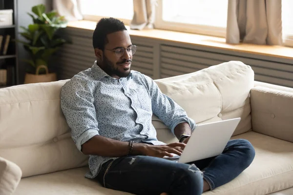 African guy enjoy lazy weekend web surfing using notebook — Zdjęcie stockowe