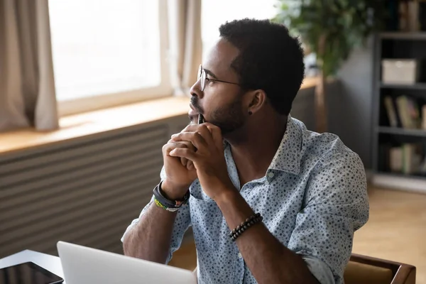 Guy sitting at table pondering over problem looking at distance — Φωτογραφία Αρχείου