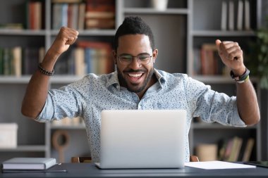Happy african guy looking at pc screen scream with joy