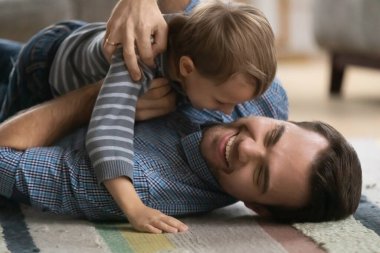 Close up happy father and little son cuddling on floor