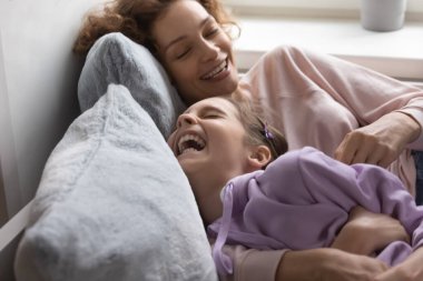 Playful mom and teen daughter have fun at home