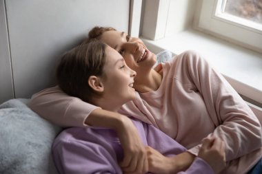 Happy mom and teenage daughter relax in bed together