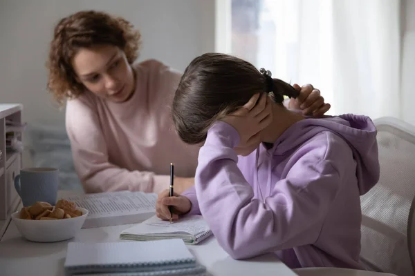 Loving mom help unhappy daughter with school homework — Zdjęcie stockowe