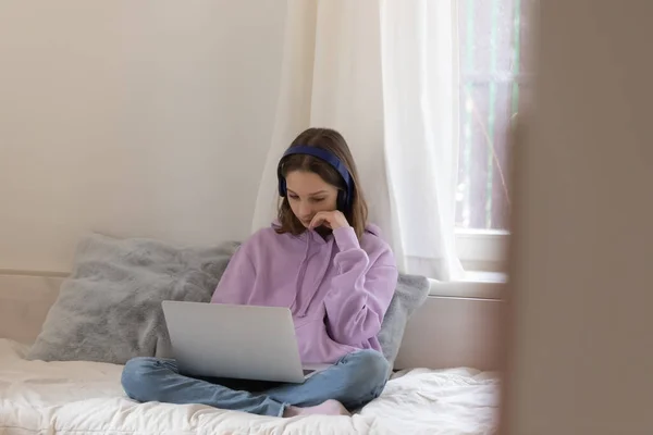 Adolescente triste sentar na cama usando laptop em casa — Fotografia de Stock