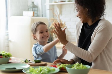 Daughter give high five to african mom cooking together indoor
