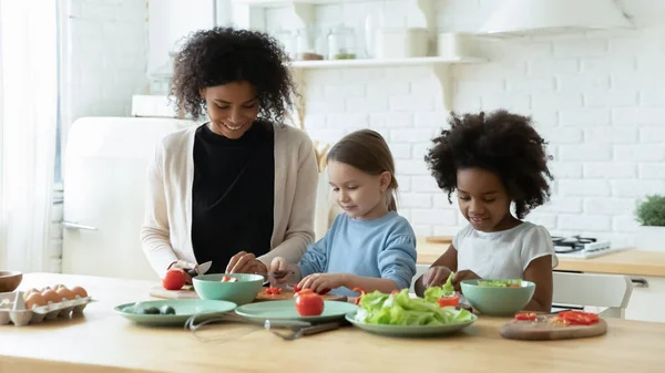 African mum two daughters cutting fresh vegetables preparing salad — Stok fotoğraf