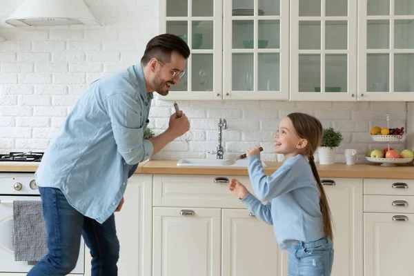 Dad and little daughter singing in kitchen enjoy weekend fun — Stok fotoğraf