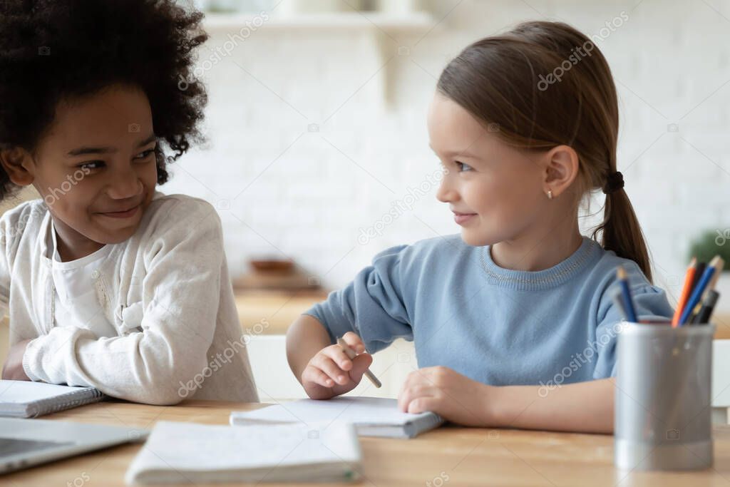 Multi-ethnic girls sit at table learning school subject together