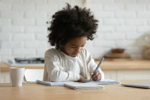 African girl sitting doing homework learn school subject at home — Stock Photo, Image