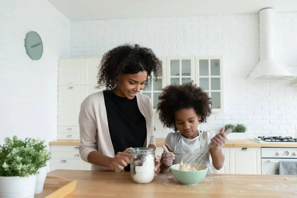 Piccola figlia africana e madre che cucinano insieme torta in cucina — Foto Stock