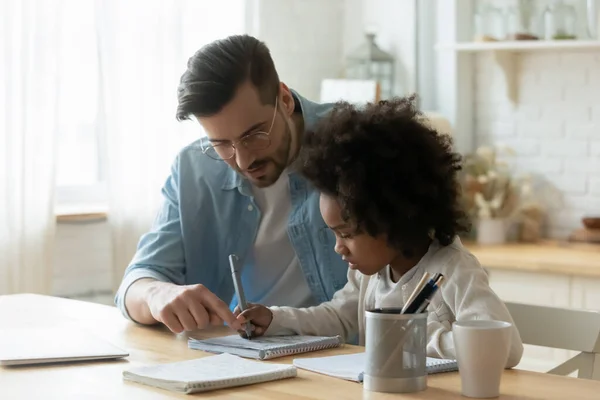 Male tutor helps understand arithmetic task to little African girl — 图库照片