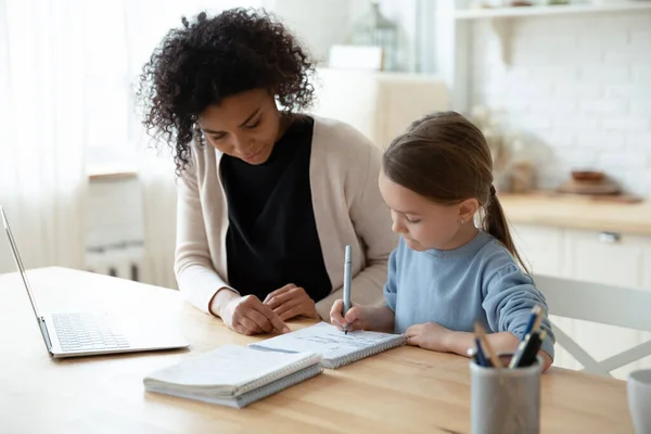 African tutor helps with school subject to little kid girl — стокове фото