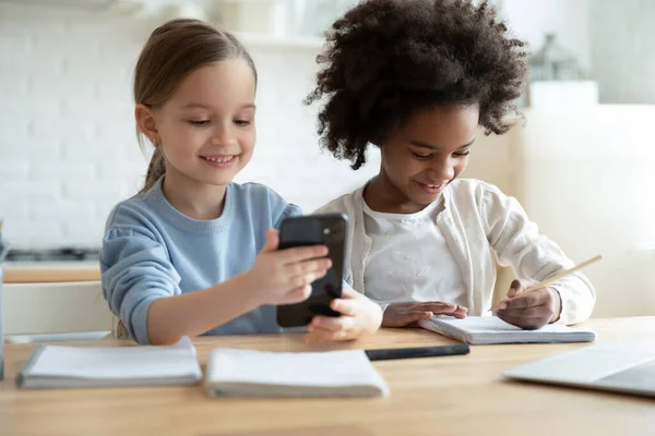 While african sister studying, another girl having fun using smartphone — Stock Photo, Image