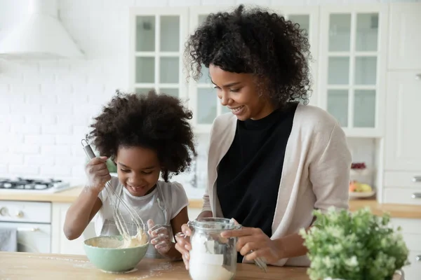 Little daughter and African mother cooking together in kitchen — Stock Photo, Image