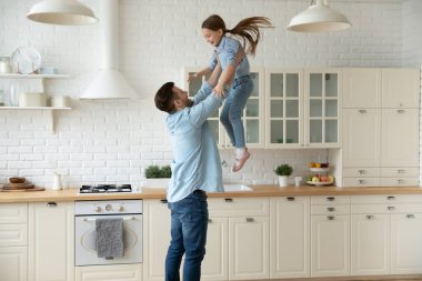 Happy father lifting up throws in air little daughter