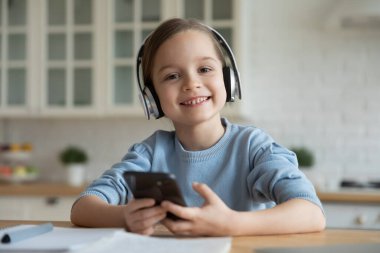 Schoolgirl study at home using wireless headphones and smartphone application