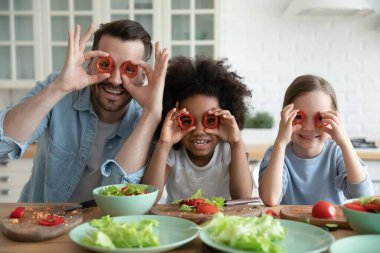 Dad and daughters cooking having fun covering eyes with paprika