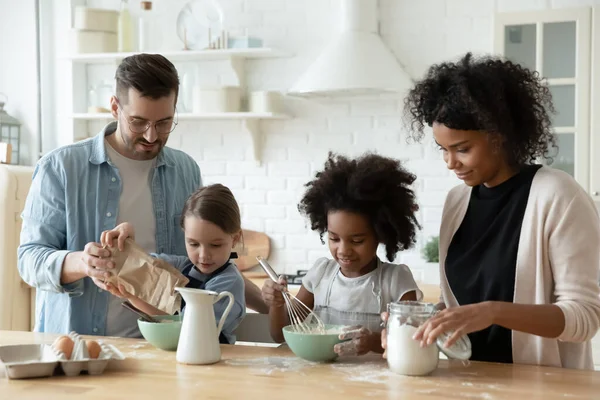 Família multirracial com crianças cozinhando doces reunidos na cozinha — Fotografia de Stock