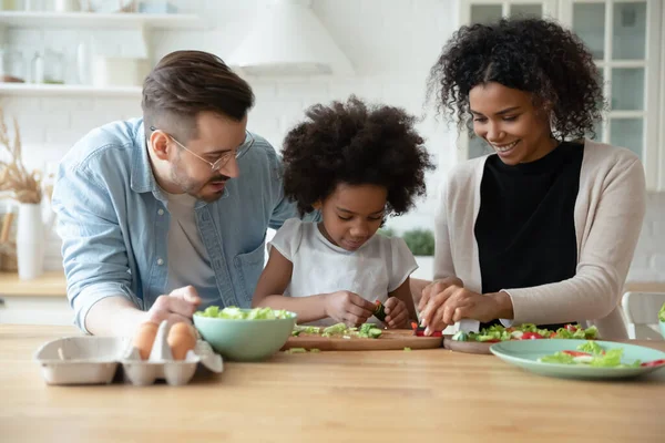 Loving multiethnic parents teach biracial small daughter cooking in kitchen — Stockfoto