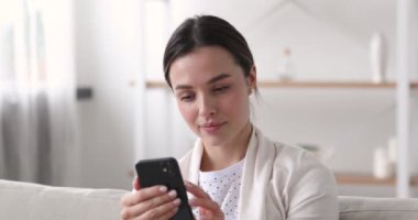 20s girl holding smartphone in hands, communicating with friends.