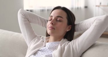 Mindful young beautiful woman meditating or daydreaming on comfortable sofa.
