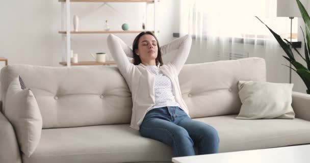 Peaceful young beautiful woman resting on comfortable couch. — Stockvideo