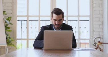 Ofisteki kurumsal yazılımı kullanarak dizüstü bilgisayarda çalışan gülümseyen iş adamı