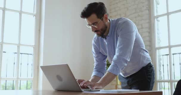 Сосредоточенный бизнесмен печатает корпоративную почту, работая на компьютере в офисе — стоковое видео