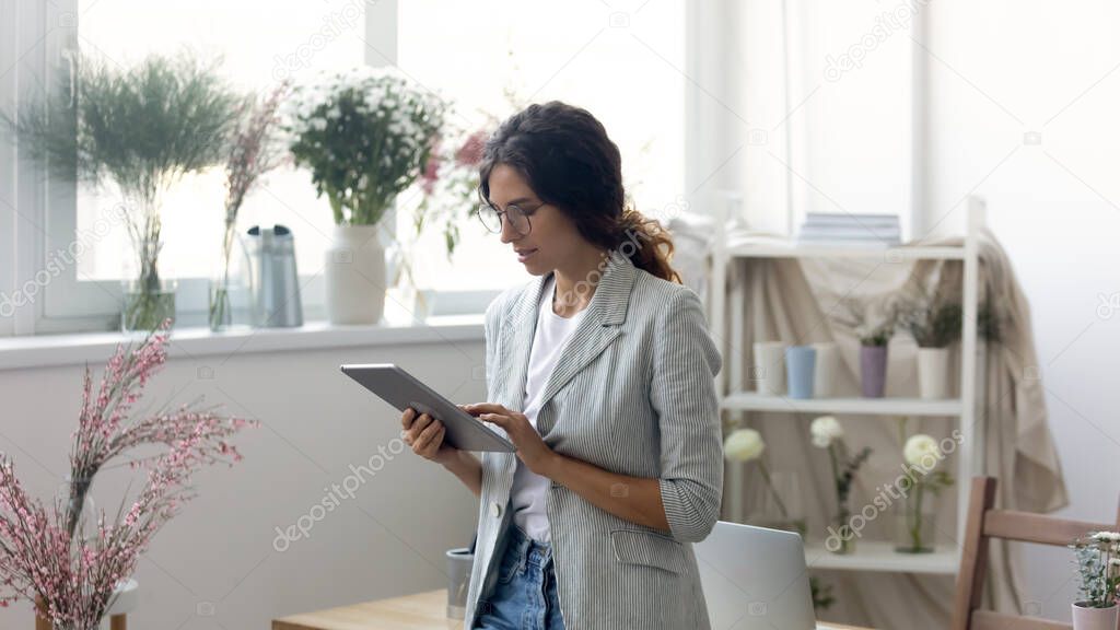 Young female florist consult client on tablet gadget