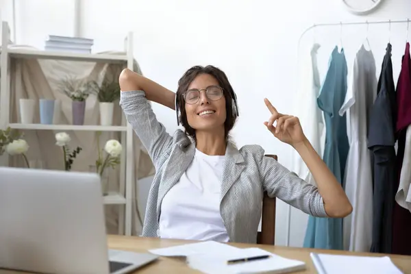 Bonne jeune femme écouter de la musique dans les écouteurs sur le lieu de travail — Photo